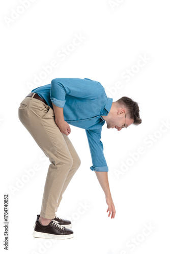 Happy casual man bending over and reaching down
