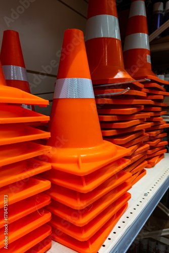 Orange traffic cones stacked neatly on a shelf in a store, showcasing safety equipment for construction and road work activities in the city