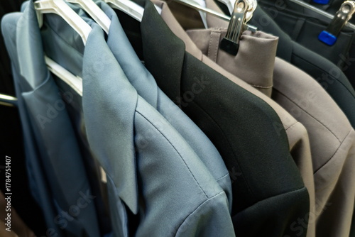 Collection of neatly hung formal jackets in various colors displayed in a clothing store during the day