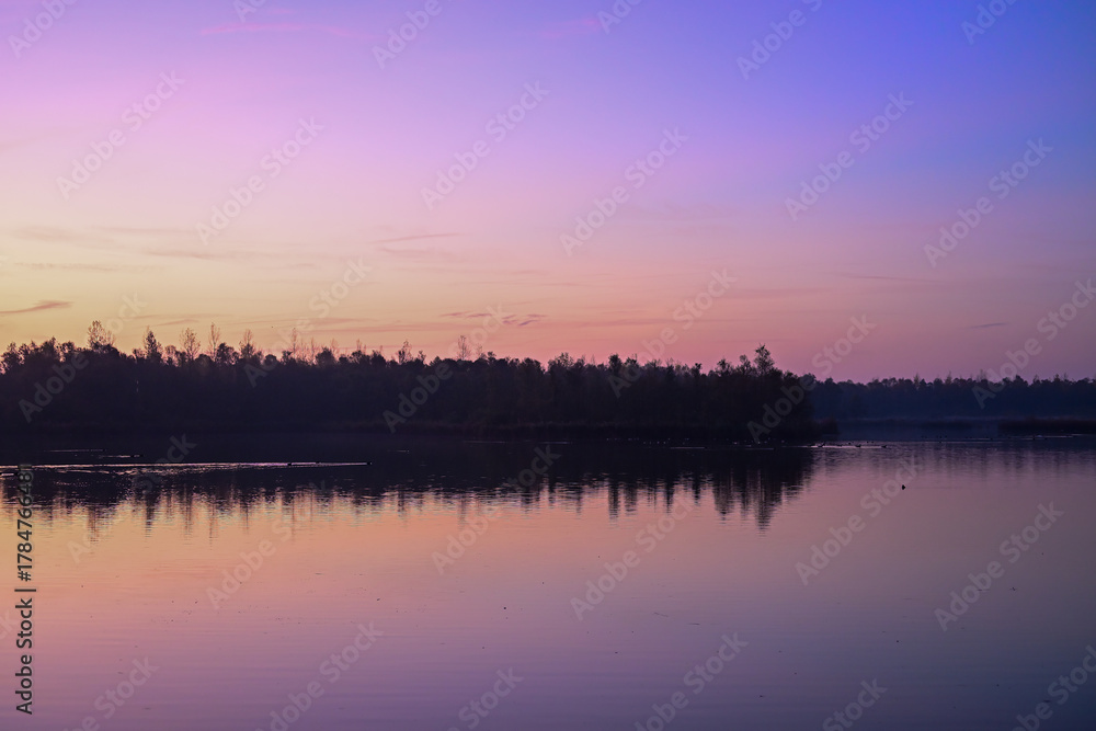 Fototapeta premium Vibrant Pre-Dawn Hues: Intense Pink and Purple Sky Reflected in Biesbosch Water