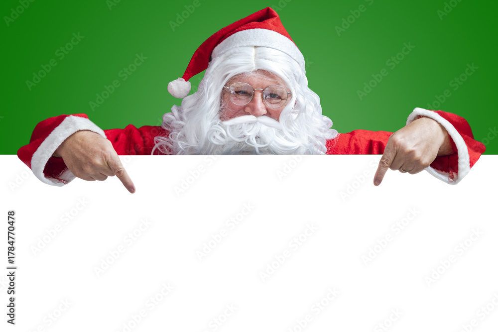Naklejka premium Santa Claus Pointing at Blank White Sign on Green Background for Christmas Holiday Promotions and Advertising