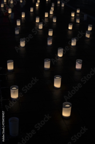 Many small paper lanterns lit up in a dark room with a warm glow and soft shadows on the floor.