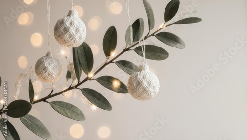 Elegant Christmas decorations hanging from a leafy branch with soft bokeh lights.
