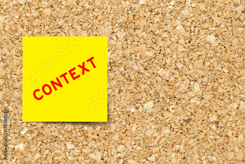 Yellow note paper with word context on cork board background with copy space