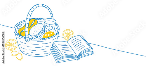Picnic basket with food and drink next to open book and lemon slices Keywords: picnic, basket, food, drink, book, reading, leisure, summer