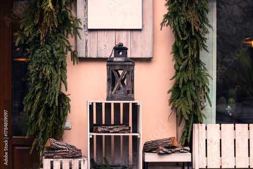 Fototapeta Naklejka Na Ścianę i Meble -  street decorative small elements Christmas eve time wooden box and lantern frame on a street with building walls and spruce branches background view