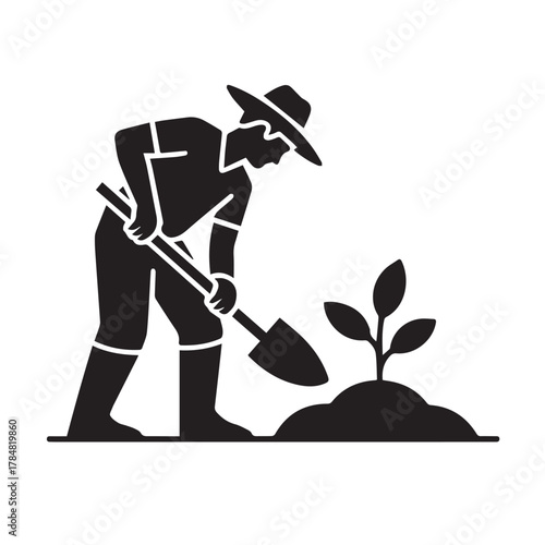 Farmer planting seedling in soil with shovel
