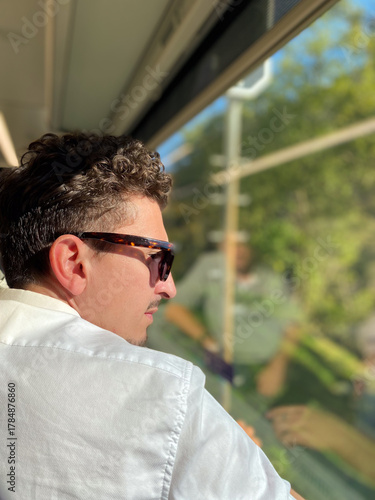 a man sitting on a train looks at the landscape from the window.