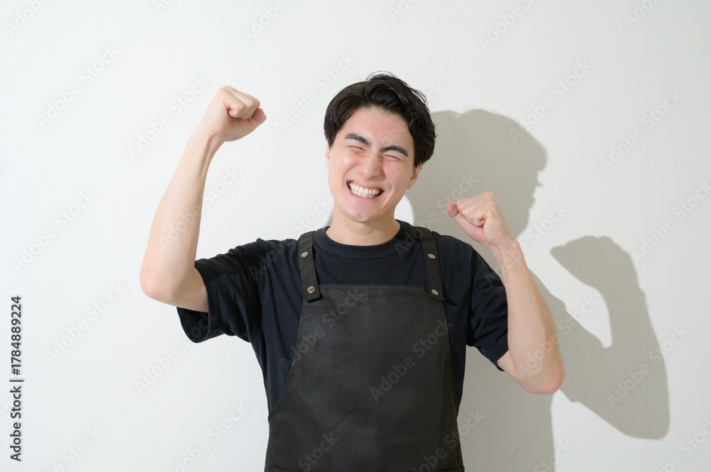 Fototapeta premium ガッツポーズをするエプロンをつけた日本人男性
