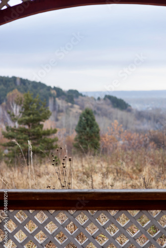 Dry grass is visible from the gazebo against a backdrop of forest and hills. 