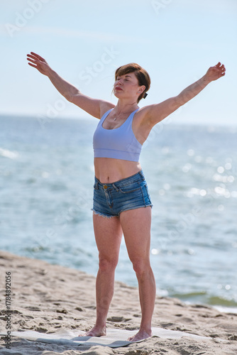 Young woman practicing yoga with raised arms on Baltic Sea beach
