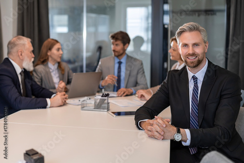 Wallpaper Mural Portrait of businessman sitting at his desk in the office and smiling looking at camera Torontodigital.ca