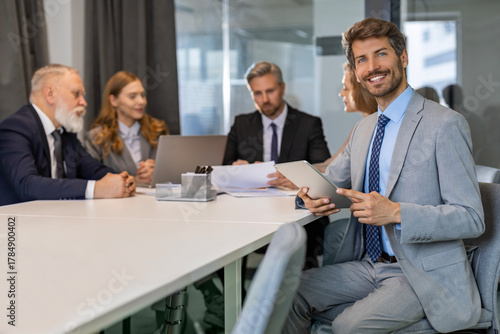 Portrait of adult businessman sitting at his desk in the office and smiling looking at camera