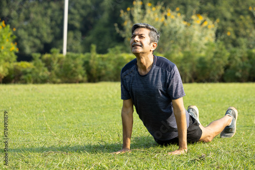 Peaceful Indian Senior Man Practicing Upward-Facing Dog Yoga Pose on Grass