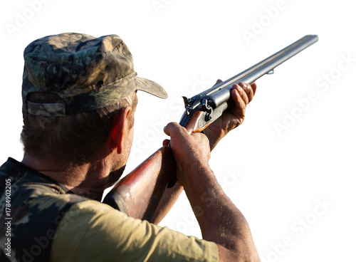 An adult hunter hunts in the autumn countryside. He fires a shotgun.