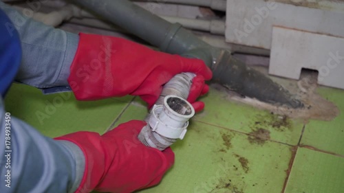 disconnect the white siphon pipe, a plumber in gloves disconnects the siphon pipe from the sewer, repair the sewer in the bathroom