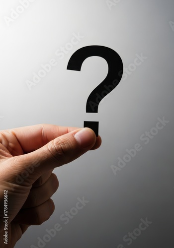 Hand holding a paper question mark cutout