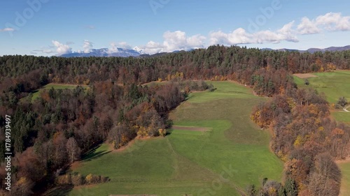 Aerial drone fly-up view revealing the Kamniško-Savinjske Alps in the background. Scenic mountain landscape with forests and valleys showcasing Slovenia’s natural beauty.