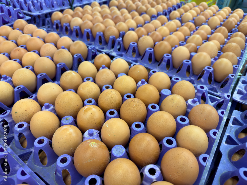 Obraz premium Rows of brown eggs on purple trays in a market setting