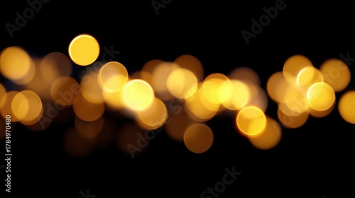 Soft glowing yellow Christmas lights blurred on dark black background, festive bokeh