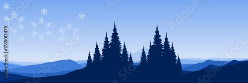 Wide screen Christmas background with a cold mountain range coniferous trees and falling snowflakes perfect for a holiday header.