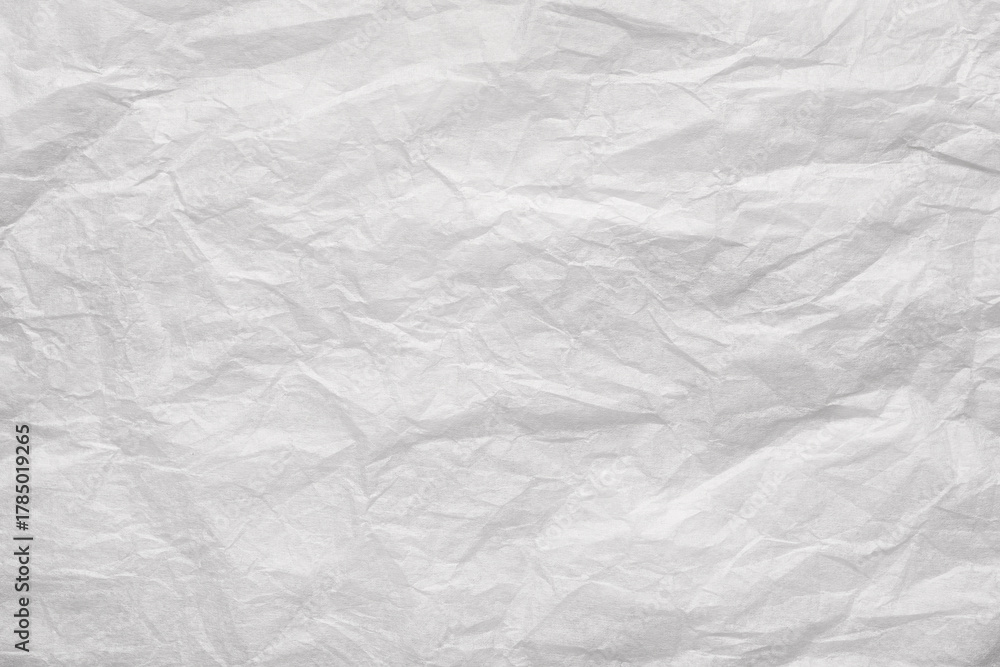 Fototapeta premium Crumpled white paper sheet with creases and wrinkles forming textured, distressed abstract background with copy space and vintage feel