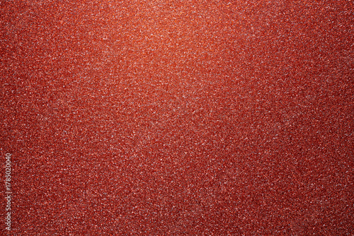 Red glitter textured paper showing gleaming particles, suitable for festive, celebration, or luxurious concepts