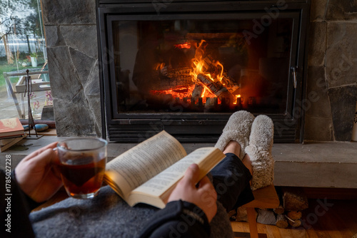 Winter relaxation with book and tea near fireplace