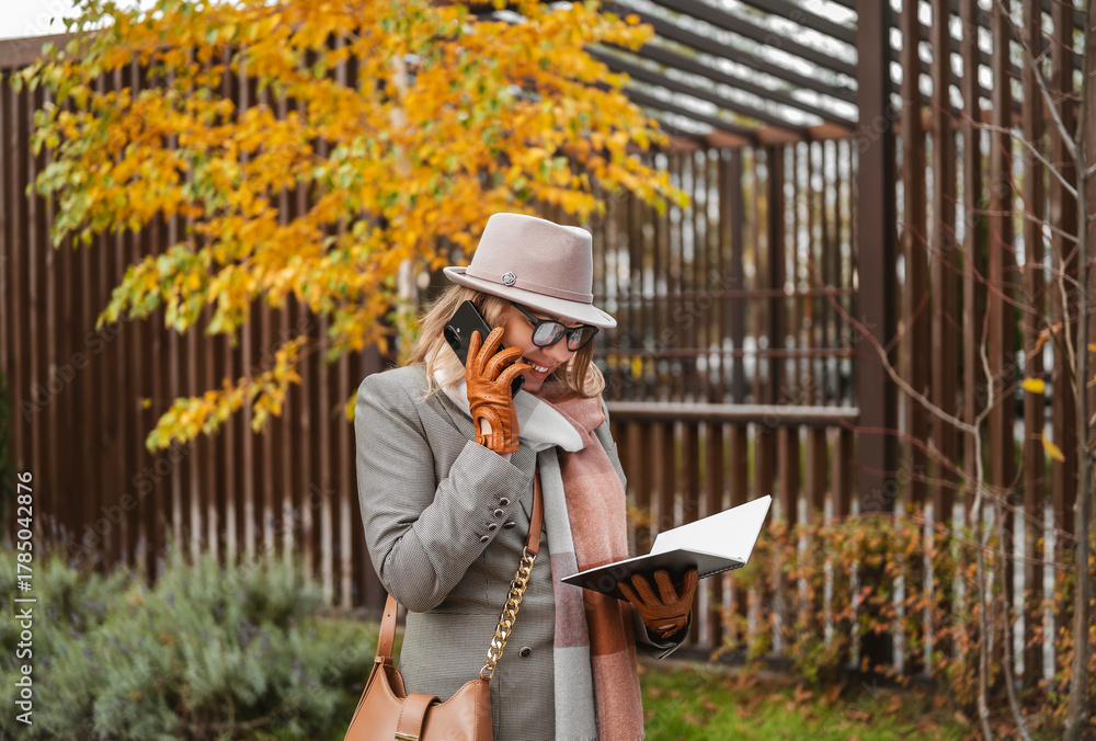 Fototapeta premium Blonde businesswoman enjoying outdoor conversations connecting with smartphone in a stylish autumn setting