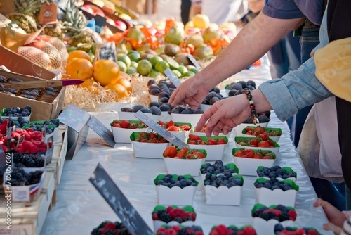 Clients en train de choisir des fruits et légumes frais sur un marché ensoleillé de Nice, côte d'azur