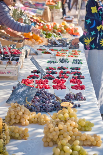 Clients en train de choisir des fruits et légumes frais sur un marché ensoleillé de Nice, côte d'azur