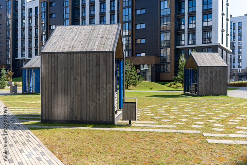 Modern wooden playhouses in urban park setting, sunny day, ideal for children's activities and community spaces, copy space
