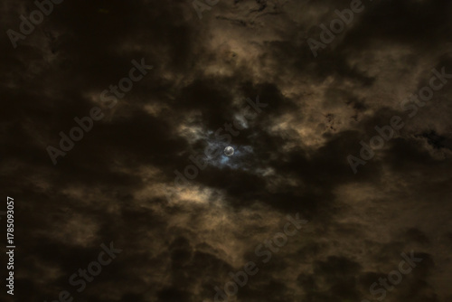 Moon shines through clouds with dramatic blue and gold colored halo 