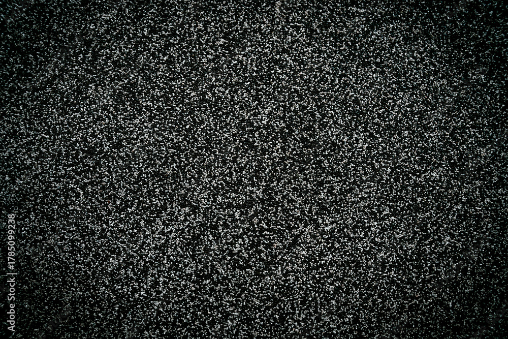Fototapeta premium Texture of asphalt surface with small gravel stones. Dark rough road background with detailed grainy pattern. Close-up. Selective focus.