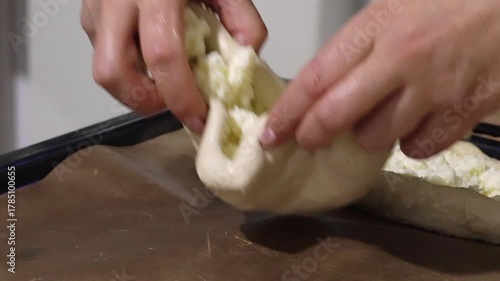 Woman placing prepared dough pieces on a baking tray, the dough is shaped into boats and filled with shredded suluguni cheese, she is preparing a Georgian cuisine dish, khachapuri