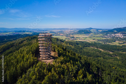 Fototapeta Naklejka Na Ścianę i Meble -  Aerial view of Dzikowiec Wielki observation tower surrounded by green forest and mountains with tourists on top. Concept of sightseeing, outdoor tourism and recreation