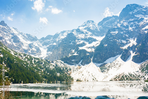 landscape with lake in tatra mountains of poland in spring. snow covered rocky peaks. outdoor adventure and vacation season on morskie oko