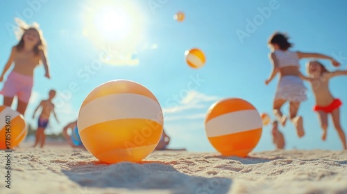 Children playing on sunny beach with colorful beach balls in summer