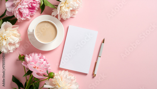 Cup of coffee with flowers, notebook and pen on pink background