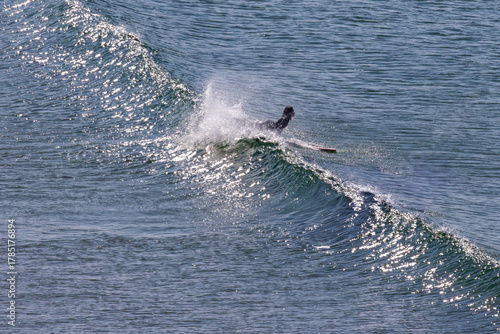 Surfer riding a sparkling wave in bright sunlight