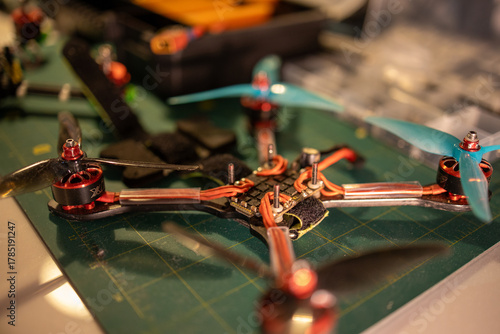 detailed close up of a quadcopter drone resting on a workbench with vibrant propellers and intricate components, neutral background, clear negative space, clean composition, balanced framing