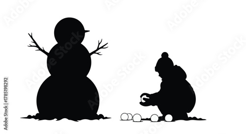 Child's silhouette happily building a snowman on a snowy winter day