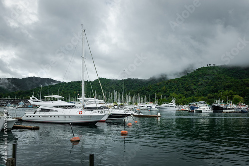 Calm marina filled with boats and yachts, surrounded by misty green hills and overcast sky creating serene atmosphere in Trinidad and Tobago