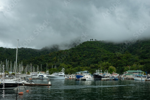 Papier peint Marina with boats beneath misty forested hills and calm waters