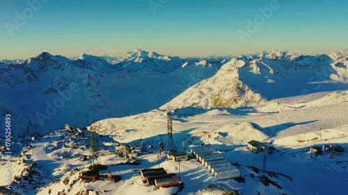 An aerial view of the snow covered Titlis mountain in the Swiss Alps. The footage captures the rugged, icy peaks and a modern cable car station, highlighting the pristine winter environment and the in