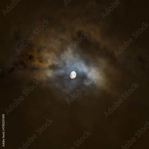 Moon shines through clouds with dramatic blue and gold colored halo