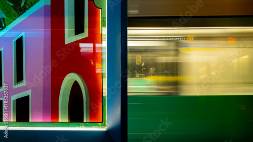 Light rail station at night with storefront in background 