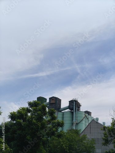 Industrial silos and storage tanks with trees under clear sky