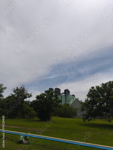 Industrial silos and storage tanks with trees under clear sky