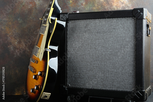 Electric guitar Epiphone Les Paul Standard with a Marshall guitar amplifier against a brown concrete wall.